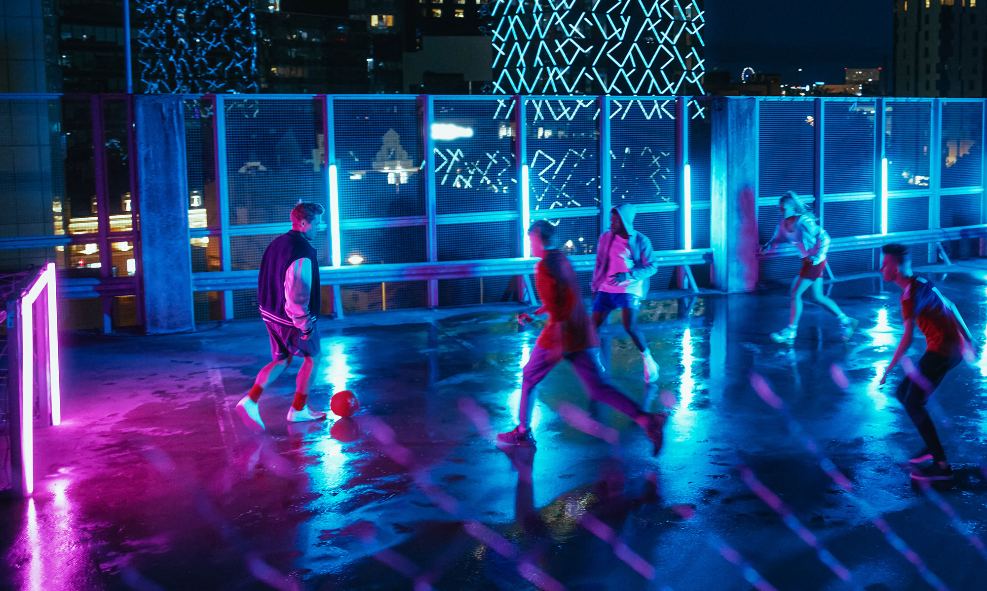 Night basketball game on rooftop lit with neon lights