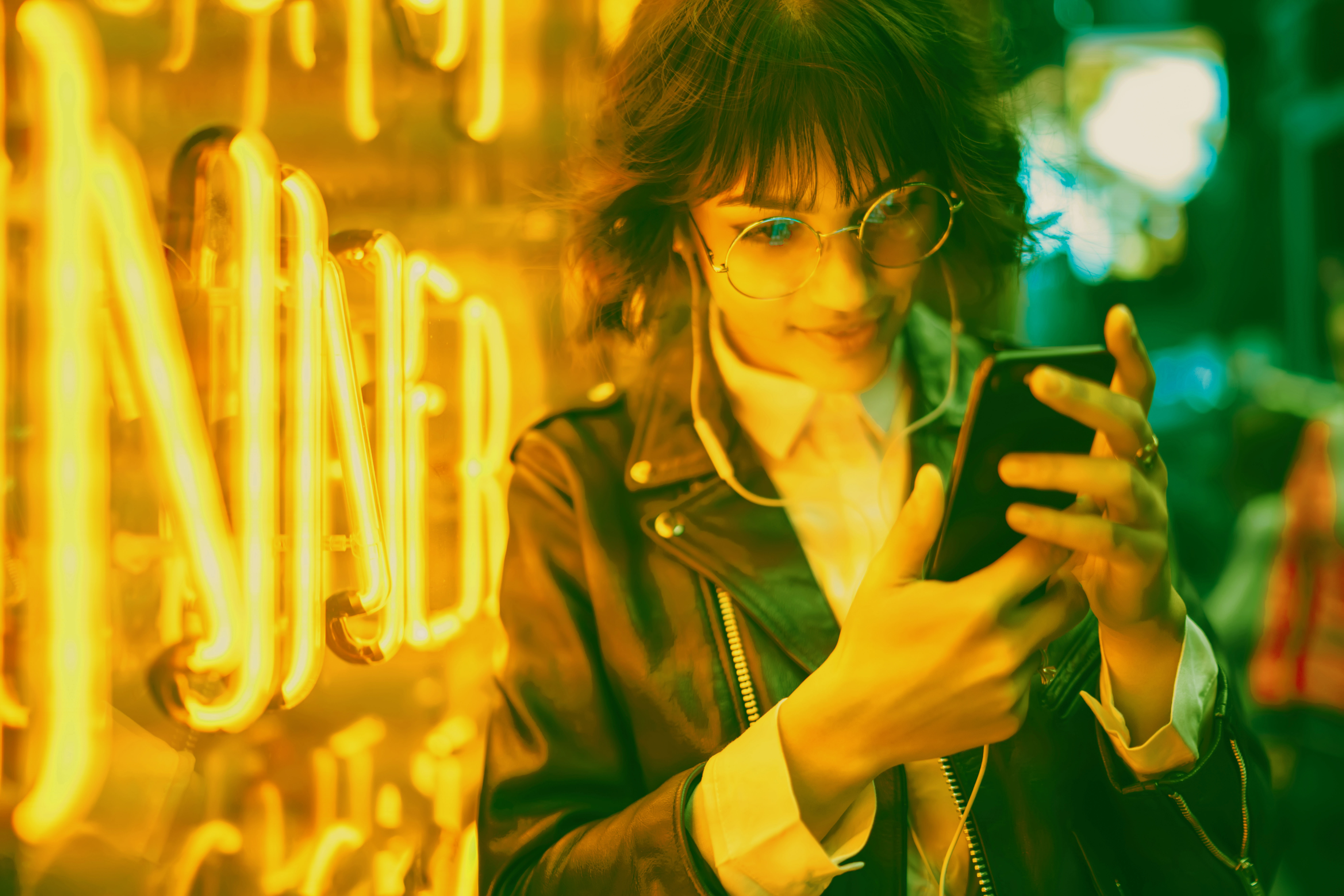 Woman by neon sign looking at cell phone
