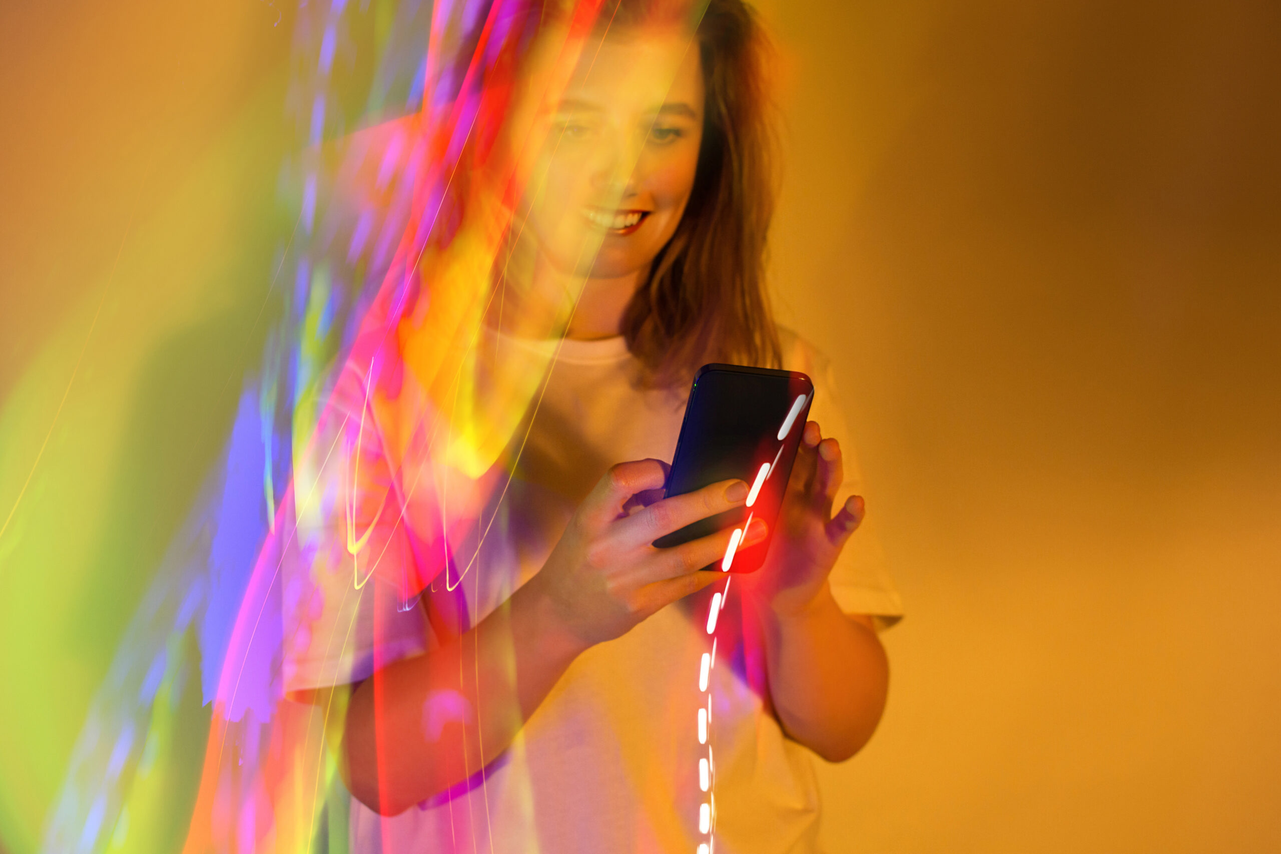 AdobeStock_709326737-edited Woman looking at phone yellow background and neon light effect