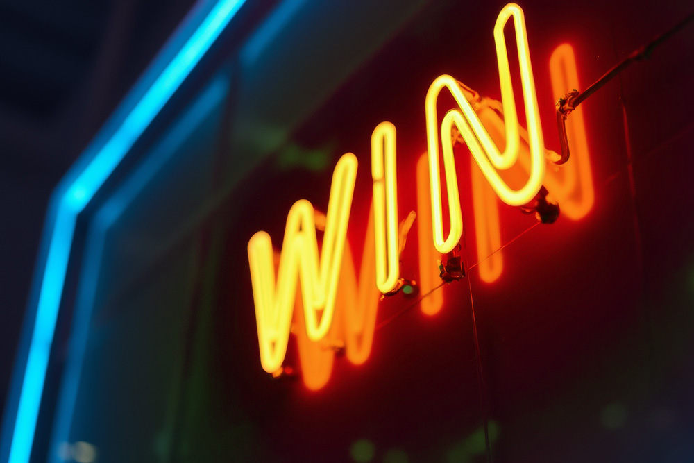 bright neon "WIN" sign glowing against a dark background 
